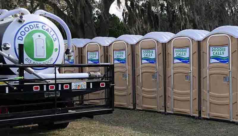 Row of tan Doodie Calls porta potties outside with a Doodie Calls pump truck nearby